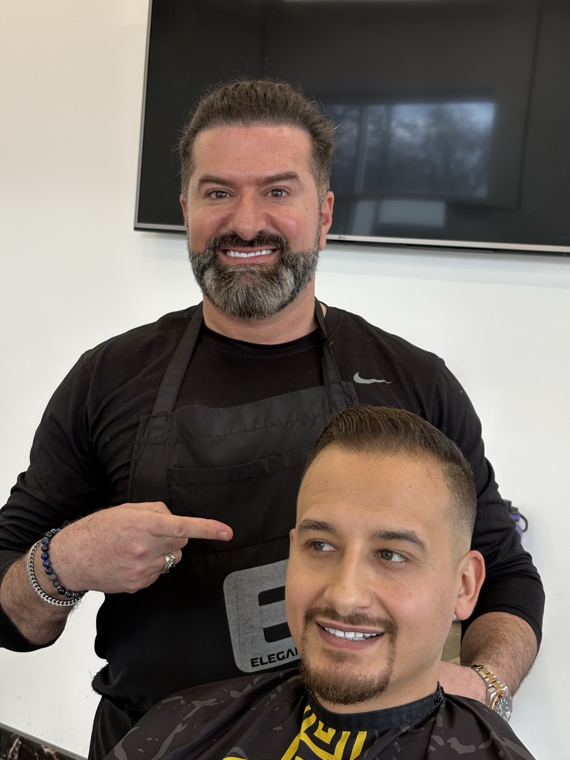 Barber presenting finished haircut on adult client