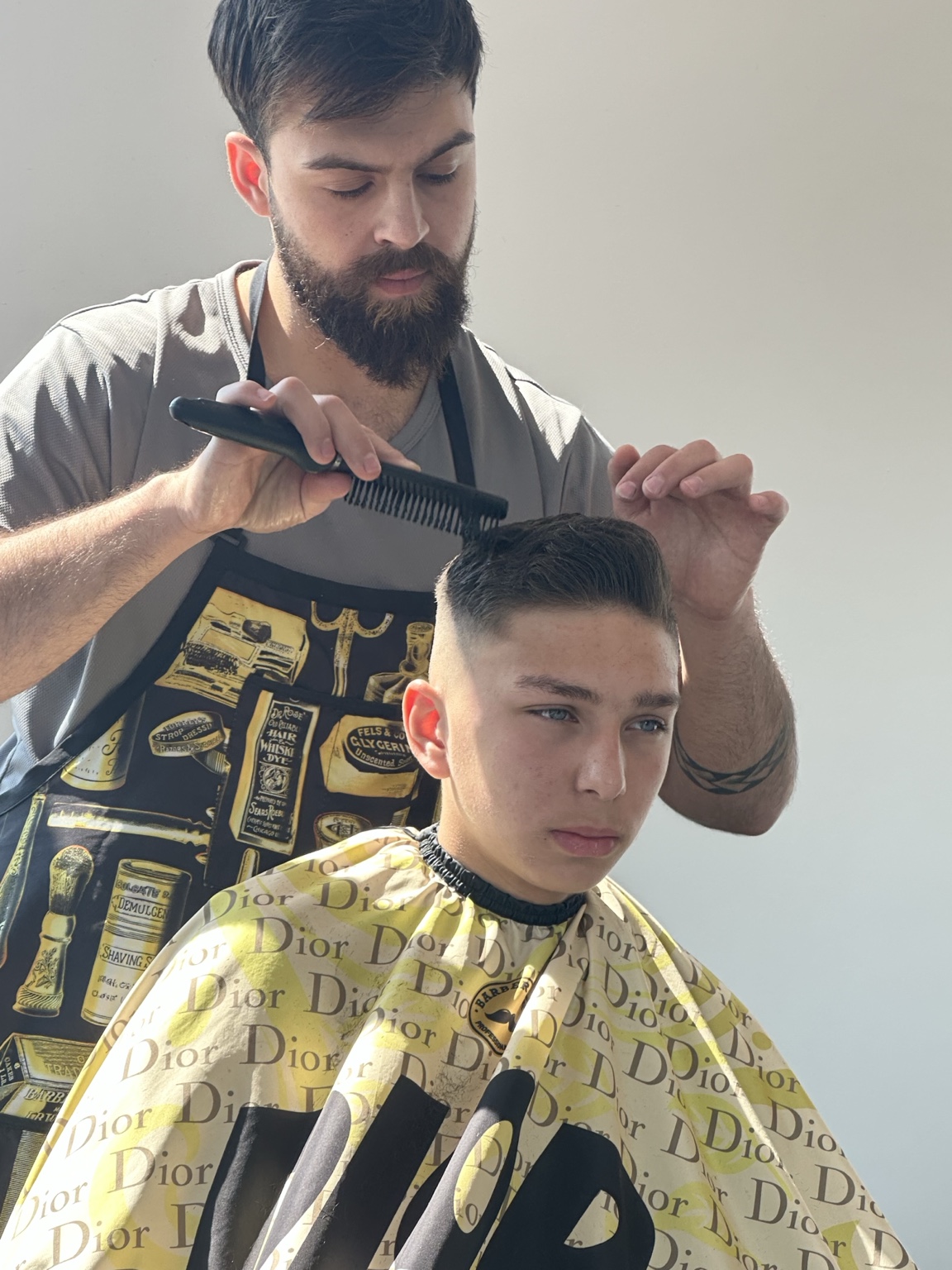 Barber cutting teen with mid fade